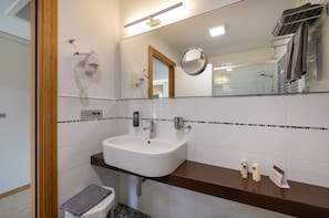 A modern bathroom with a white sink, a mirror, and a towel rack.