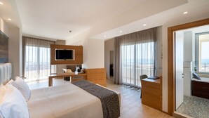 Ein modernes Hotelzimmer mit einem großen Bett, einem Schreibtisch, einem Fernseher und einem Balkon mit Blick.