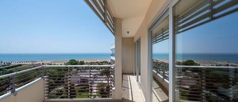 A balcony with a view of the sea, a table, and a chair.