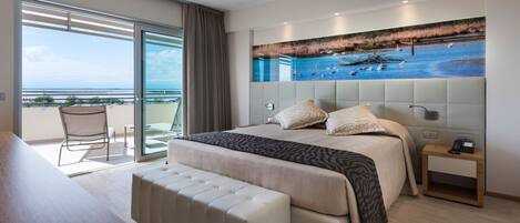 A hotel room with a large bed, a balcony with a view, and a painting of a beach scene.