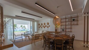 A modern dining area with a round table, wicker chairs, and a hanging light fixture.