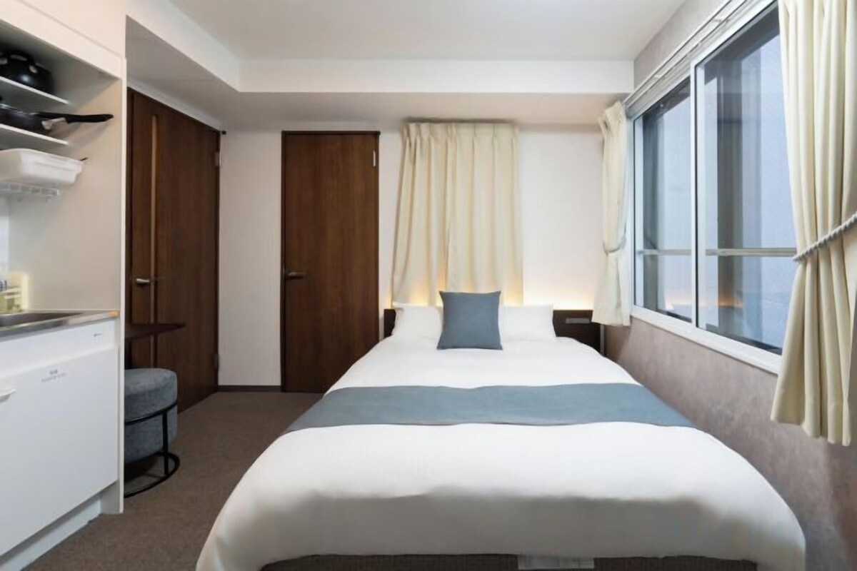 A hotel room with a bed, a desk, a chair, and a window.