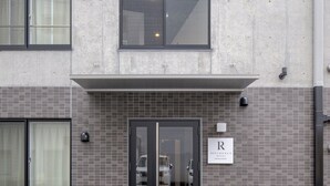 Een modern gebouw met een betegelde gevel, een glazen ingang en een bord waarop 'residentiehotel' staat.