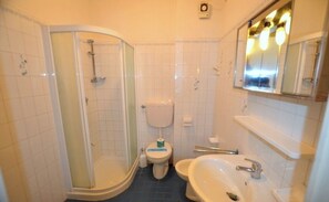 Une salle de bain avec une douche à parois de verre, des toilettes et un lavabo.