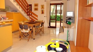 A kitchen with a dining table, chairs, and a TV. - Perfect holiday home with fenced garden in Lignano Pineta (Lignano Sabbiadoro)