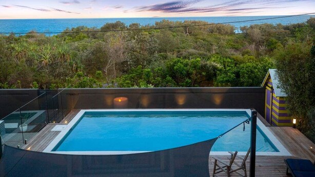 A swimming pool with a view of the ocean and surrounding greenery.