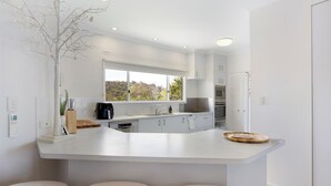 A modern kitchen with white cabinetry, a large island, and a view of the outdoors.