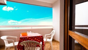 Ein Balkon mit Tisch und Stühlen, Blick zum Himmel und Holzgeländer.