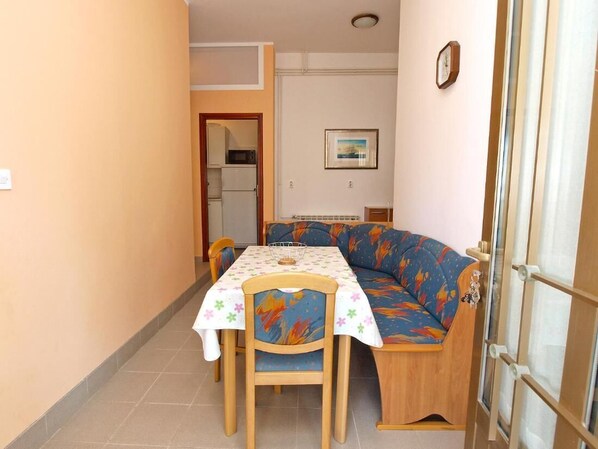 A dining area with a table and chairs, a sofa, and a door leading to another room.