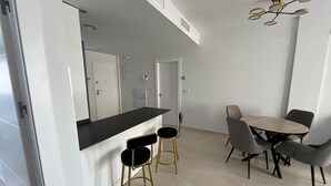 A modern kitchen with a black countertop, two gold stools, and a dining table with four chairs.