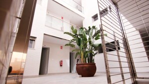 A modern building with a white facade, a fire extinguisher, and a potted plant in the center.