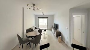 A modern living room with a dining area, a TV on a cabinet, and a ceiling fan.