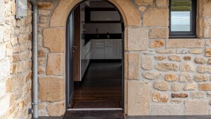 A stone building with a tiled roof, an archway entrance, and a small window.