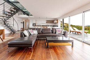 A modern living room with a sectional sofa, a coffee table, and a staircase.
