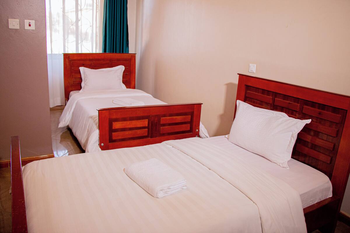 A hotel room with two beds, each with wooden headboards and white bedding.