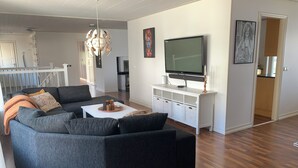 A modern living room with a sectional sofa, a flat-screen TV, and a white entertainment unit. - Ronneby Torneryd Retreat (Ronneby)