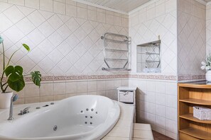 A bathroom with a large bathtub, a towel rack, a small shelf with baskets, and a potted plant. - Ronneby Torneryd Retreat (Ronneby)