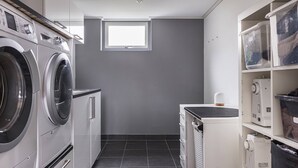 A laundry room with a washing machine, dryer, and stacked plastic bins on shelves. - Ronneby Torneryd Retreat (Ronneby)