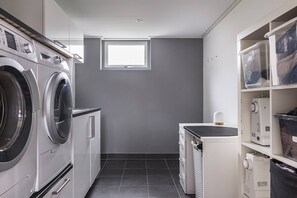 A laundry room with a washing machine, dryer, and stacked plastic bins on shelves.