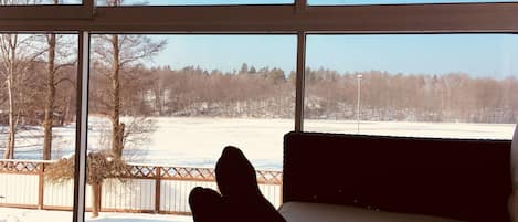 A room with large windows overlooking a snowy landscape with trees and a fence.