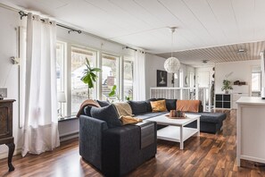 A modern living room with a dark sofa, white coffee table, and a view of the outdoors through large windows. - Ronneby Torneryd Retreat (Ronneby)