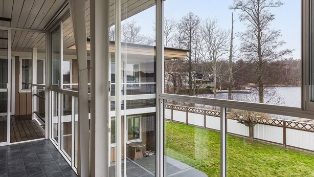A modern building with large glass windows and a balcony overlooking a grassy area and a body of water. - Ronneby Torneryd Retreat (Ronneby)