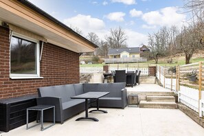 An outdoor patio with a sofa and table, a brick house, a white fence, and a grassy area. - Ronneby Torneryd Retreat (Ronneby)