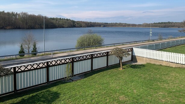 A lakeside walkway with a fence, a grassy area, and a clear view of a lake. - Ronneby Torneryd Retreat (Ronneby)