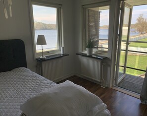 A bedroom with a bed, a window with a view of a lake, a radiator, and a potted plant. - Ronneby Torneryd Retreat (Ronneby)