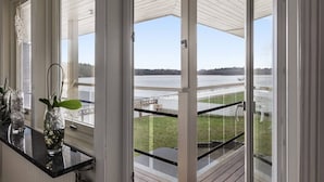 A room with large windows overlooking a body of water and a dock. There are potted plants on a window sill. - Ronneby Torneryd Retreat (Ronneby)