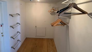 Una habitación con suelo de madera, un radiador blanco, una puerta con cerradura y un proyector instalado en el techo.