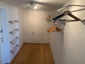 Una habitación con suelo de madera, un radiador blanco, una puerta con cerradura y un proyector instalado en el techo.