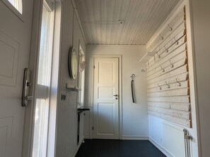 A hallway with a white door, a radiator, a wall-mounted mirror, and a coat rack. - Ronneby Torneryd Retreat (Ronneby)