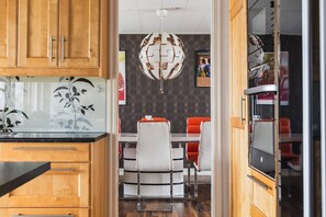 Una cocina moderna con armarios de madera, una mesa de comedor con superficie de vidrio y una lámpara esférica original.
