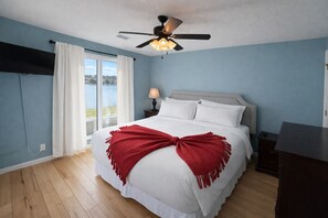 A bedroom with a bed, a ceiling fan, a nightstand, a lamp, and a view of a body of water. - Shorefront Escape at TRL (Kimberling City)