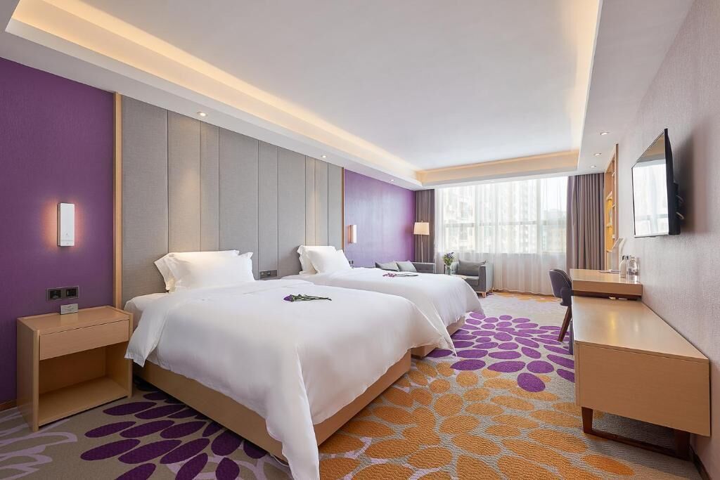 Een hotelkamer met twee bedden, een bureau, een stoel en een televisie.