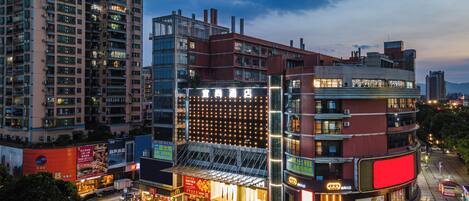 A multi-story hotel with a prominent glass facade, a rooftop terrace, and a ground-level restaurant.