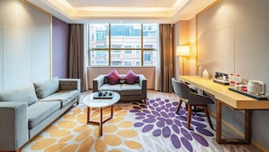 A modern hotel room with a sofa, a small table, a desk, and a view of the city through large windows. - Echarm International Hotel Guangzhou Baiyun International Airport Huadu Plaza Branch - Free Deliver Service to Guangzhou Baiyun International Airport & Free Deliver Service to Canton Fair Complex During Canton Fair Period (Guangzhou)