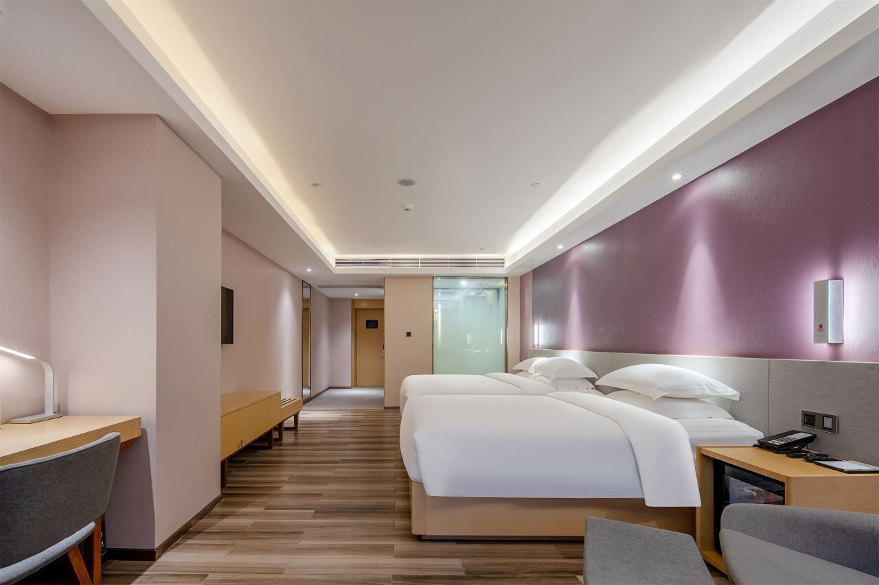 A modern hotel room with a large bed, a desk, and a seating area.