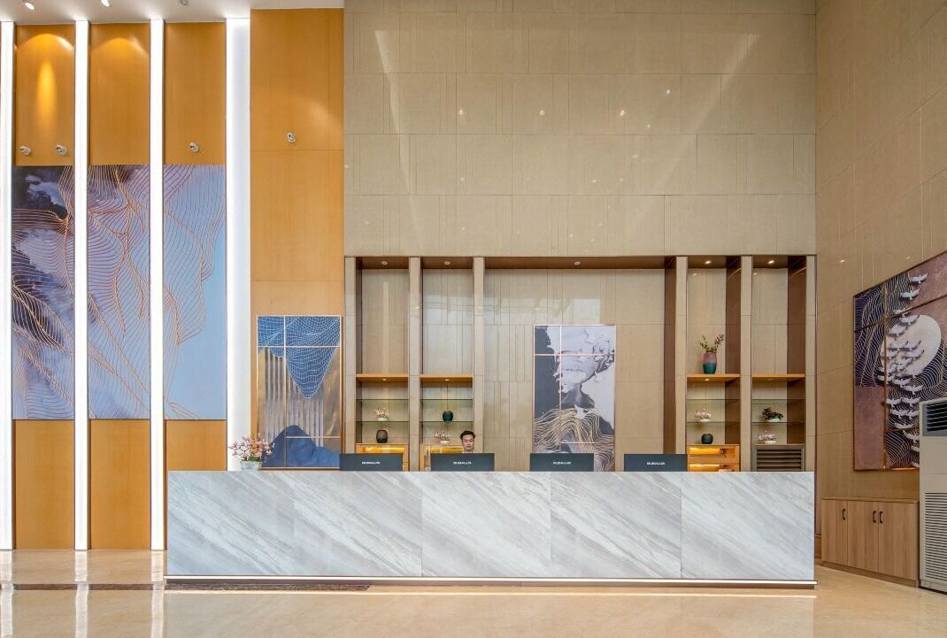 A reception desk with a marble top, flanked by vertical wooden panels and artwork.