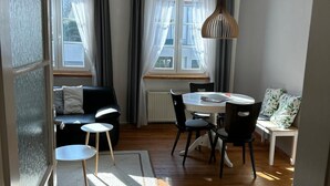 Un salon moderne avec un plancher en bois, un canapé, une table à manger avec des chaises et un luminaire suspendu.