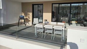 An outdoor seating area with a table and chairs, a small table with a lamp, and a chair.