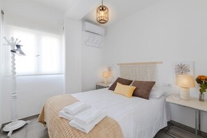 Une chambre à coucher bien rangée, avec un lit, des tables de chevet, une lampe et un élément décoratif mural.