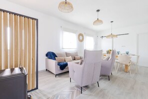 A modern living room with a sofa, armchairs, a dining table, and pendant lights. - Rustic Escape by Fidalsa (Ibi)