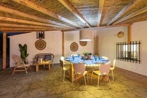 A dining area with a round table, chairs, and a ceiling with exposed beams.