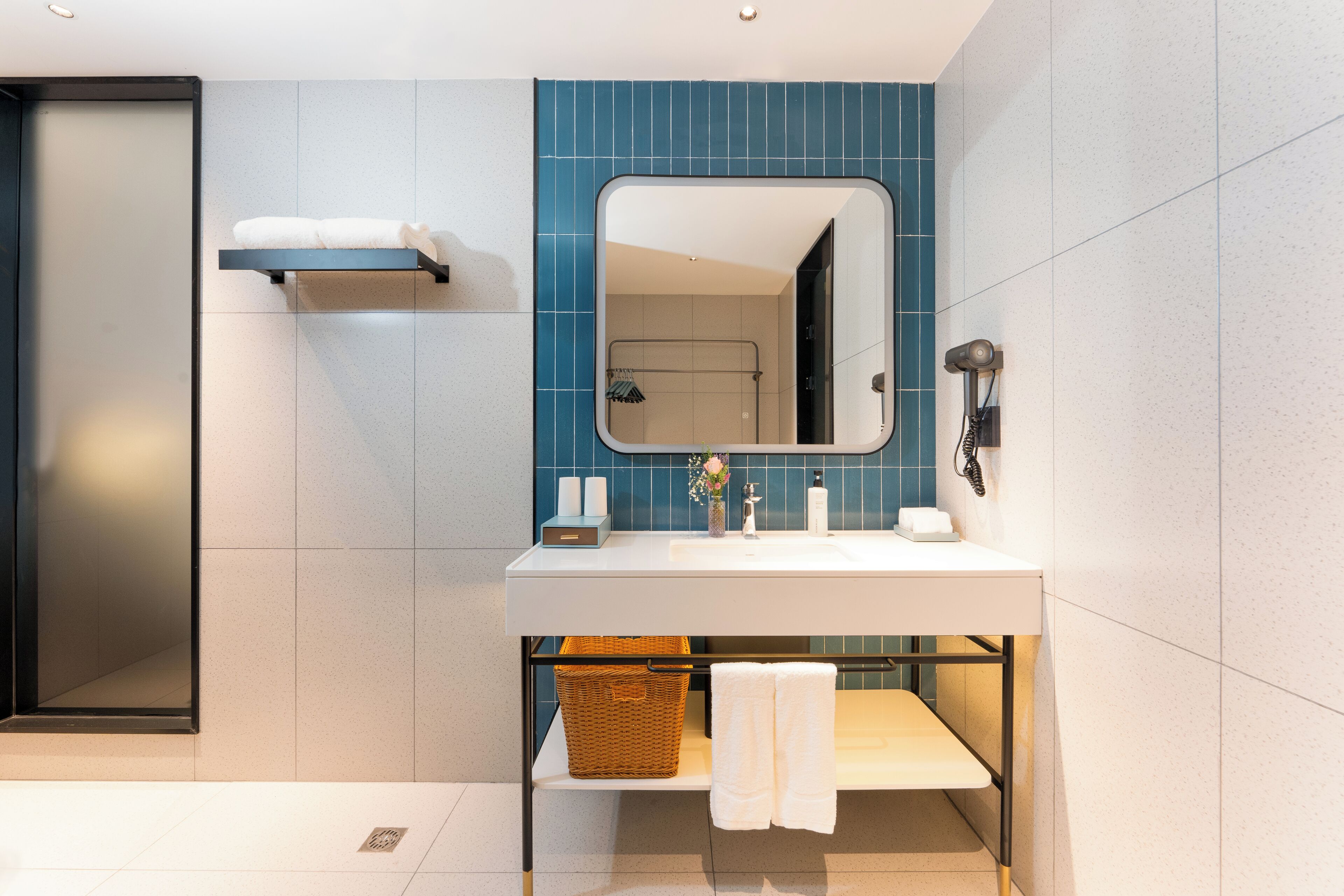 A modern bathroom with a large mirror, white sink, and a towel rack.