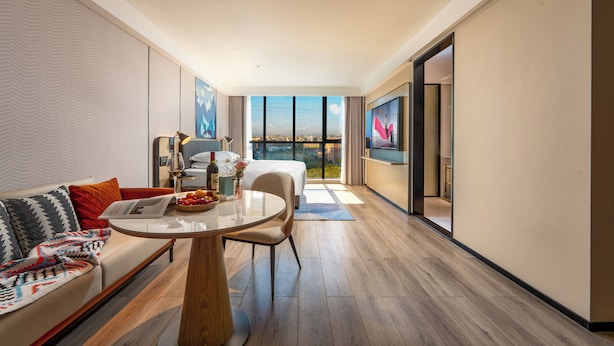 A modern hotel room with a balcony, a dining area, and a large window offering a city view. - Echarm Hotel Guangzhou Baiyun International Airport T3 Terminal Branch (Guangzhou)