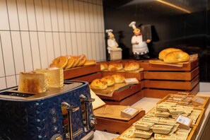 Eine Bäckertheke mit verschiedenen Brotsorten und Gebäcken, ein blauer Toaster und Kochfiguren.