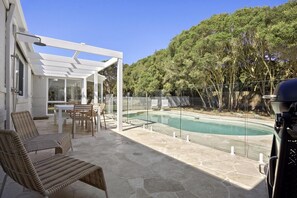 Un espacio al aire libre techado con piscina, mobiliario y una pérgola.
