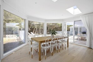 Un comedor con una mesa grande y sillas, ventanas amplias y vistas al exterior.